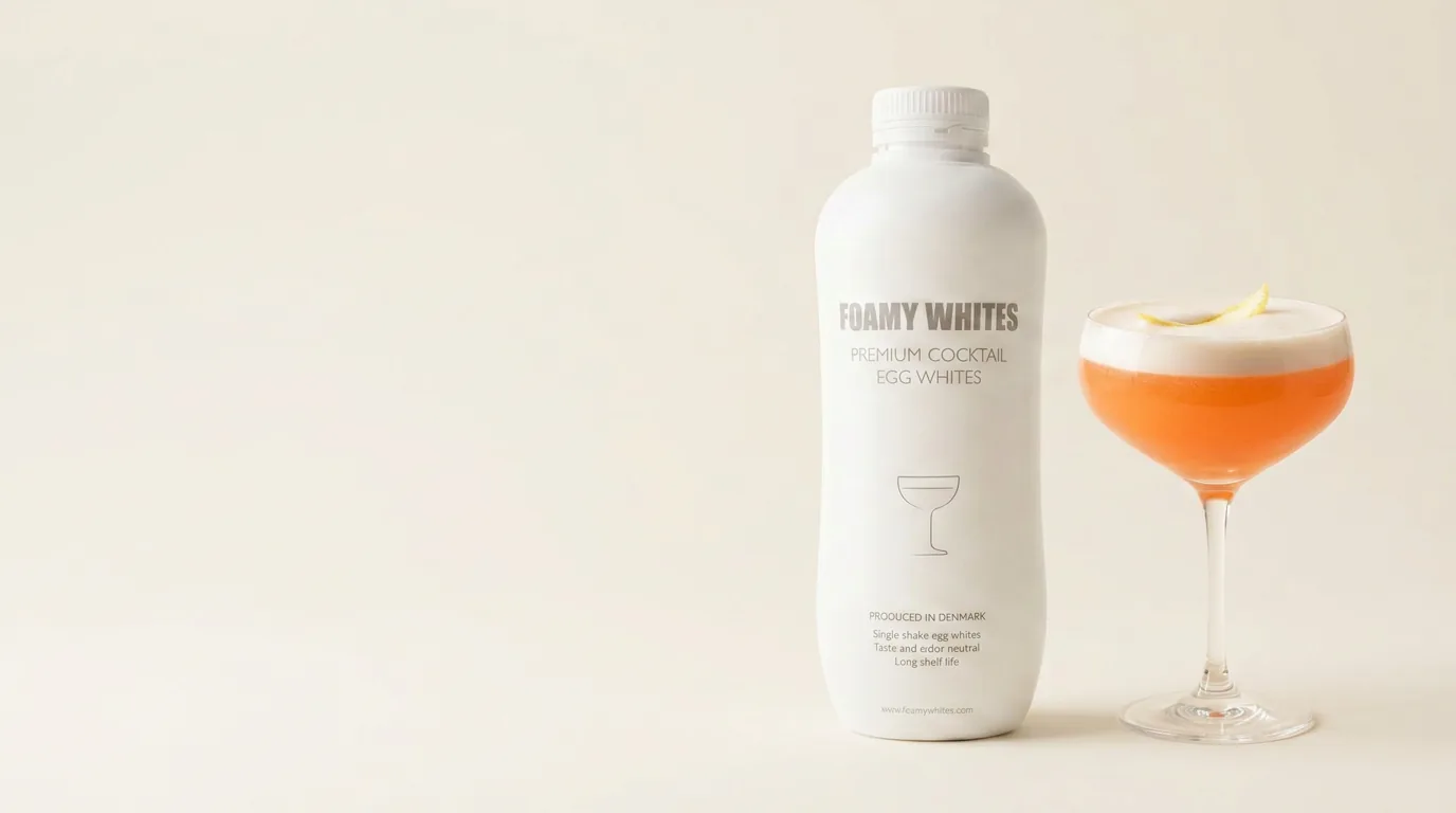 The bottle beside a finished Aperol Sour with a dense pale foam crown